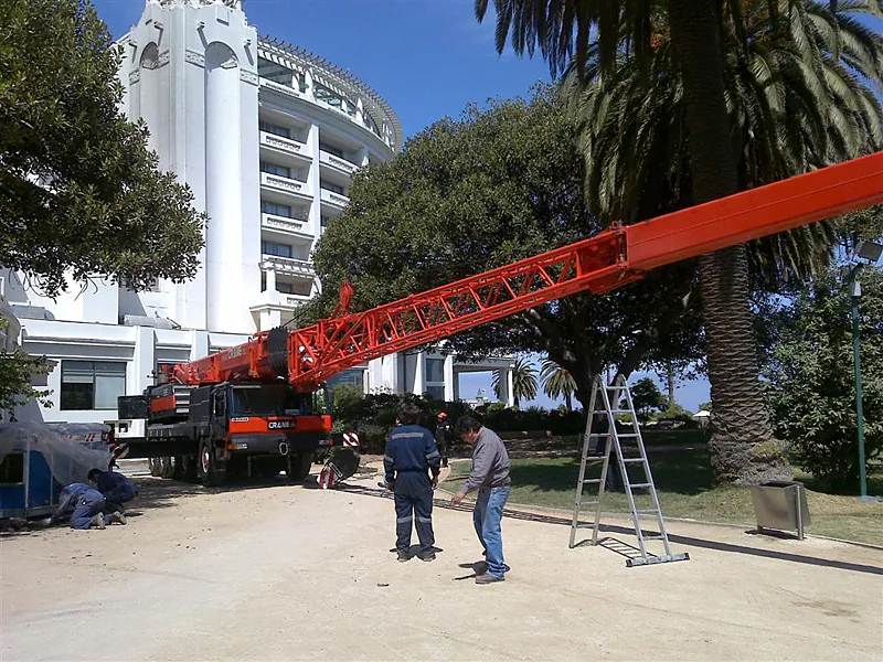 Dos trabajadores junto a la grúa telescópica de 100 toneladas de Crane Service, que da referencia de la escala del equipo