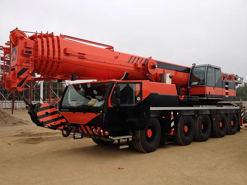 Grúa telescópica autopropulsada de 130 toneladas de Crane Service, con la pluma recogida y los estabilizadores retraídos, en terreno de faena
