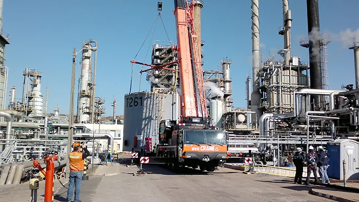 Grúa telescópica de 80 toneladas de Crane Service operando dentro de una planta petroquímica, con personal de faena con casco y ropa de alta visibilidad