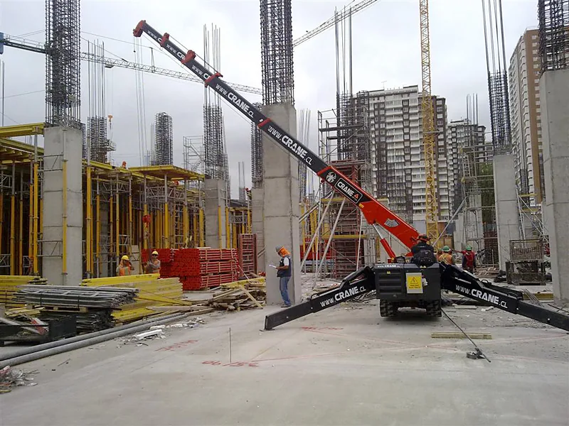 Minigrúa araña de 3 toneladas de Crane Service trabajando al pie de un edificio en construcción en altura