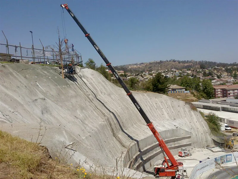La grúa de 55 toneladas con la pluma extendida sobre un canal de hormigón, trabajando desde el borde del talud