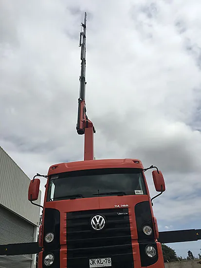 Camión pluma de 7,85 toneladas de Crane Service con la pluma recogida junto a un galpón industrial