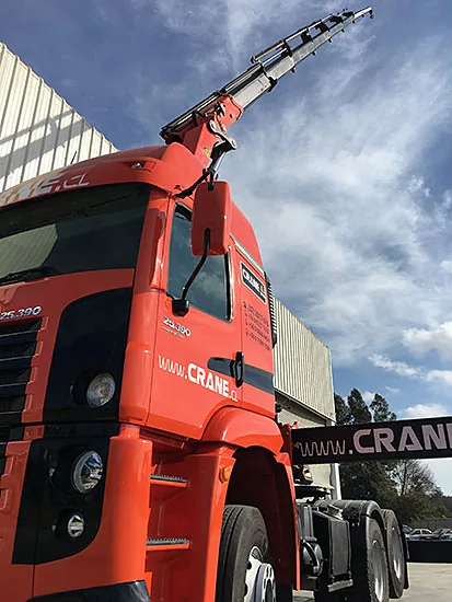 Tractocamión pluma de Crane Service con la pluma extendida contra un cielo azul